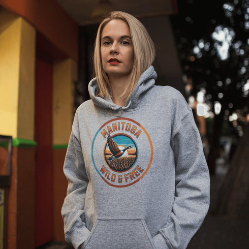 Celebrate the heart of the prairies with our Manitoba – Wild & Free hoodie, featuring a stunning graphic of a Canadian goose soaring over golden wheat fields.